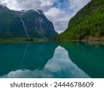 Imposing mountains and landscape, waterfalls reflections of the meltwater in the emerald green water in the Lovatnet, Lake Lodal valley, Loen, Norway.
