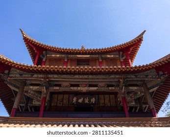 Imposing upward angle showcasing the intricate multi tiered roof structure, curved eaves, and traditional inscribed plaques of a historic Chinese pavilion. The scene represents architectural grandeur, cultural heritage, historic craftsmanship, and oriental design.