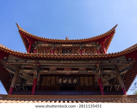 Imposing upward angle showcasing the intricate multi tiered roof structure, curved eaves, and traditional inscribed plaques of a historic Chinese pavilion. The scene represents architectural grandeur, cultural heritage, historic craftsmanship, and oriental design.