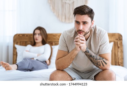 Impotence concept. Sad man presses hands to his chin and ponders, wife disappointed folded arms at bed, at interior - Shutterstock ID 1744994123