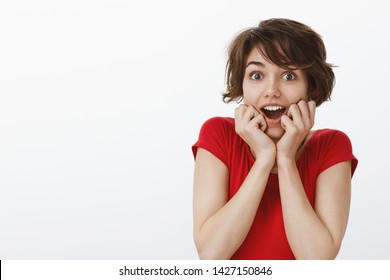 Impressed fascinated caucasian emotive enthusiastic girl short haircut open mouth astonished gasping surprised hold hands face-line stare camera excited look admiration happiness lucky news