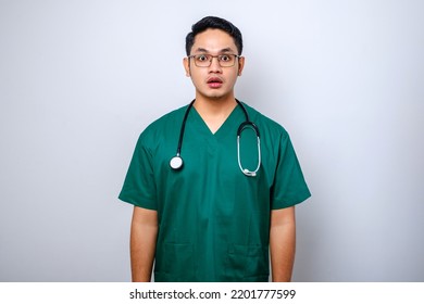 Impressed And Surprised Asian Male Nurse Or Doctor In Scrubs Drop Jaw And Stare At Camera Speechless, Looking Amazed Over White Background