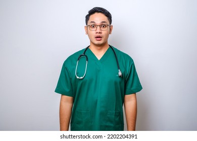 Impressed And Surprised Asian Male Nurse Or Doctor In Scrubs Drop Jaw And Stare At Camera Speechless, Looking Amazed Over White Background