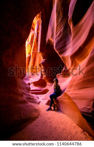 Impressed young woman looking up inside of the Antelope Canyon, Arizona, USA.