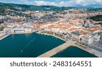 An impressive aerial shot of Trieste, Italy, featuring a majestic cruise ship docked at the port. This vibrant city, known for its rich history, stunning architecture, and bustling waterfront