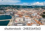 An impressive aerial shot of Trieste, Italy, featuring a majestic cruise ship docked at the port. This vibrant city, known for its rich history, stunning architecture, and bustling waterfront