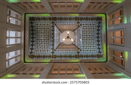 An impressive atrium view with an artfully designed ceiling mesh, illuminated by impressive lighting and a central chandelier
