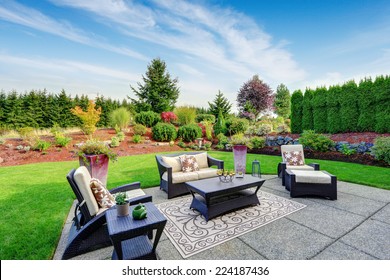 Impressive backyard landscape design. Cozy patio area with settees and table