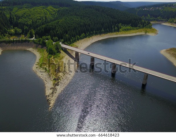 Impressive bridge crossing a sweet water lake between\
mountains covered in old tall fir trees in the national park hard,\
germany. 