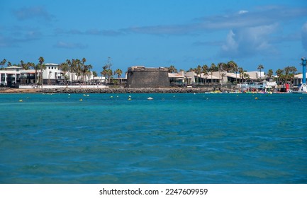 Impressive calm turquoise sea on the coast of Caleta de Fuste and tej traditional architechture at the back in the touristic Fuerteventura during a sunny day with clear blue sky in the Canary Islands. - Shutterstock ID 2247609959