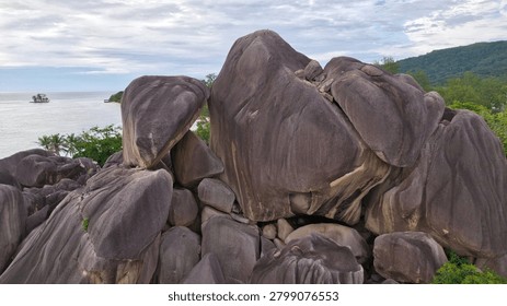 Impressive drone view showcasing a massive pile of iconic granite stone formations overlooking the ocean coast at the famous Anse Source d'Argent beach on La Digue Island, Seychelles.