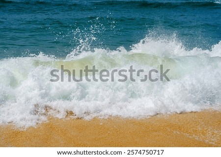 Impressive image of a dynamic ocean wave splashing on a sandy beach. The wave is captured at the perfect moment, as it crashes onto the shore, sending a burst of water and foam into the air.