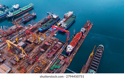 Impressive overhead drone shot capturing massive shipyard drydocks with industrial cranes and various commercial vessels undergoing maintenance and repair works.