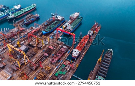 Impressive overhead drone shot capturing massive shipyard drydocks with industrial cranes and various commercial vessels undergoing maintenance and repair works.