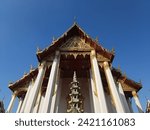 the impressive roof of Wat Suthat, a Buddhist temple in Bangkok, Thailand. The roof is decorated with intricate patterns and topped with a golden pagoda.