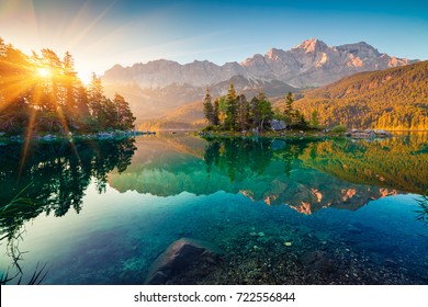 Impressive summer sunrise on Eibsee lake with Zugspitze mountain range. Sunny outdoor scene in German Alps, Bavaria, Germany, Europe. Beauty of nature concept background.
 - Powered by Shutterstock