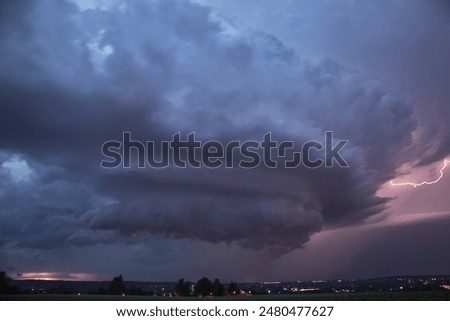An impressive supercell thunderstorm with a powerful dramatic structure and high lightning intensity 
moves across the night sky over the eastern German city of Chemnitz in summer.