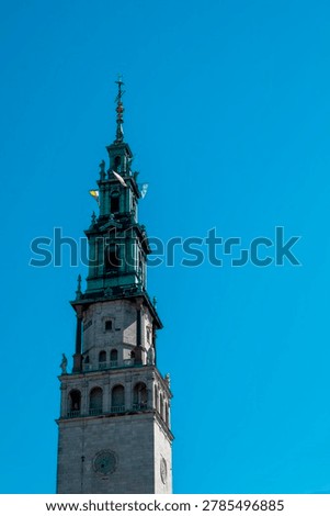 impressive tower and architectural facade of Jasna Gora Monastery in Czestochowa, Poland, set against a bright blue sky.
