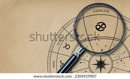 The imprint of the zodiac sign Cancer on old paper is enlarged with a lens