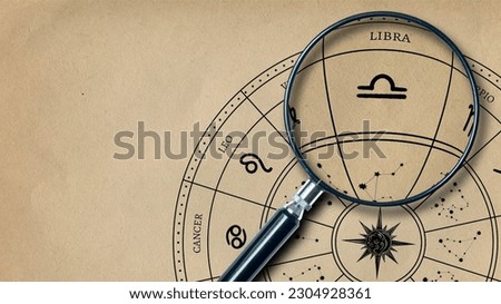 The imprint of the zodiac sign Libra on old paper is enlarged with a lens