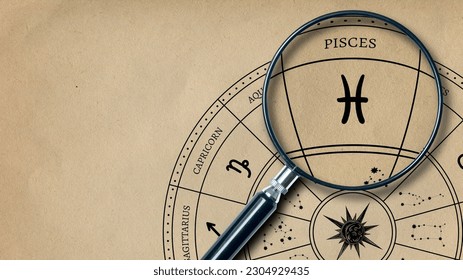 The imprint of the zodiac sign Pisces on old paper is enlarged with a lens