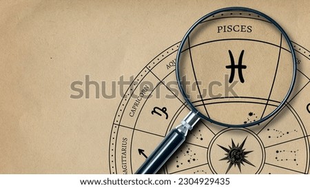 The imprint of the zodiac sign Pisces on old paper is enlarged with a lens