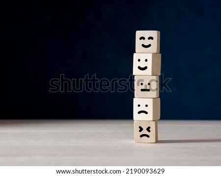 To improve customer rating, client evaluation, experience, satisfaction and achieving the best service concept. Stacked wooden cubes with emoticon face symbols.