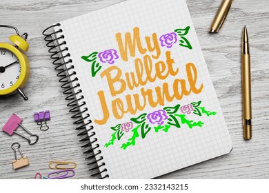 Improve your productivity. Notebook with words My bullet journal, drawn flowers, stationery and alarm clock on white wooden table, flat lay - Powered by Shutterstock