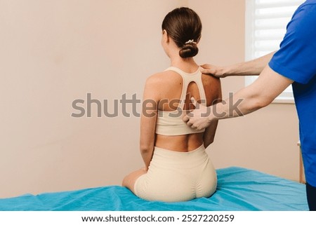 Improving back mobility in clinic. Doing osteopathy to reduce pain and muscle tension. Physiotherapist is treating upper back pain for female patient