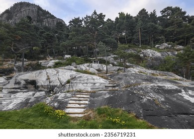 An improvised wooden staircase leading up a stone slope to a wooden bench at the top of a rocky hill. Norway. Before sunset - Powered by Shutterstock