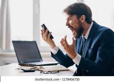 Impulsive Man Yelling Into The Phone Laptop In The Background                              