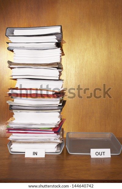 Inbox with
stack of paperwork empty outbox on
desk