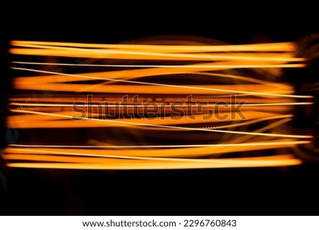 Incandescent close-up filaments in lamp glow with dim orange warm light, selective focus 