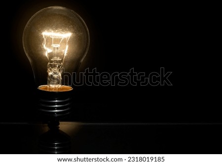 An incandescent light bulb is burning on a black background.