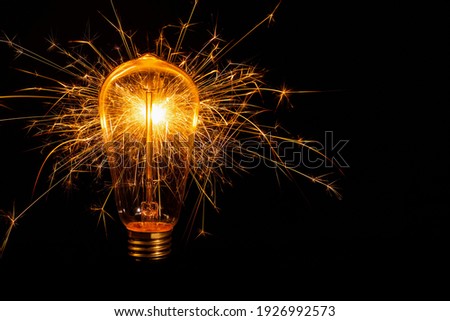 Incandescent light bulb with emitting sparks on black background