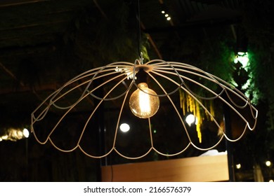 an incandescent light bulb inside a white metal chandelier in a restaurant. side view. loft style - Powered by Shutterstock