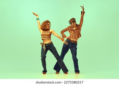 Incendiary dance. Emotional man and woman in retro style clothes dancing disco dance over green background. Concept of fashion trends of 70s, 1980s years, music, hippie lifestyle - Shutterstock ID 2275380217