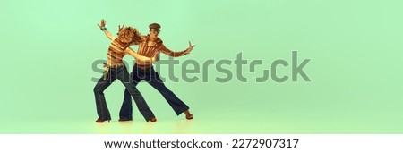 Incendiary dance. Emotional man and woman in retro style clothes dancing disco dance over green background. Concept of fashion trends of 70s, 1980s years, music, hippie lifestyle