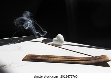 Incense Stick Smoke On White Home Table On Black Background With Heart Into Sun Light 