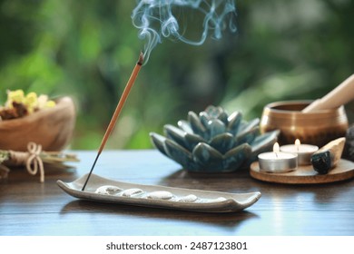 Incense stick smoldering in holder and burning candles on wooden table outdoors - Powered by Shutterstock