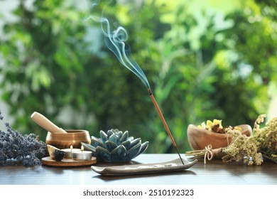 Incense stick smoldering in holder, burning candles, dry flowers and Tibetan singing bowl on wooden table outdoors - Powered by Shutterstock