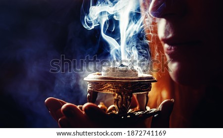 incense in a woman hand, incense smoke on a black background.