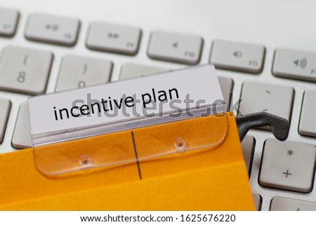 incentive plan as a term on a tab on a yellow hanging file on a computer keyboard