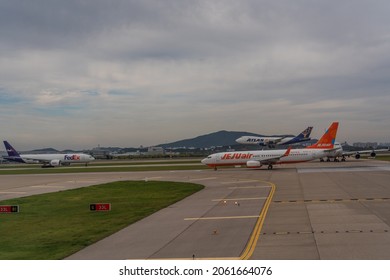 Incheon, South Korea, October 2021, Jeju Air B737 Is Ready For Departure, Fedex Boeing 777 Freighter Airplane Is Taxiing For Departure While Atlas Air B747 Is Short Before Touchdown At Incheon Airport