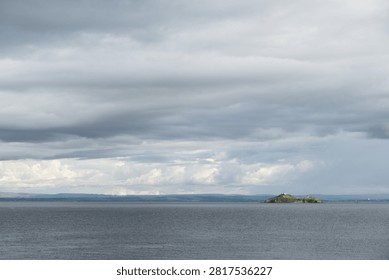 Inchkeith island in Firth of Forth under cloudy sky