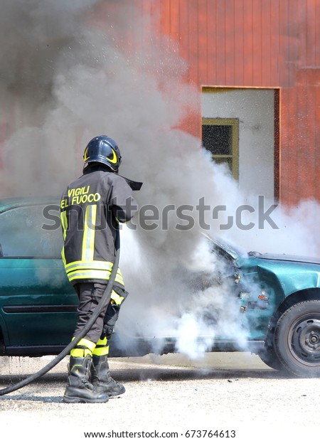 incident car\
with smoke and an Italian firefighter with the uniform with the\
written firefighters in the Italian\
language