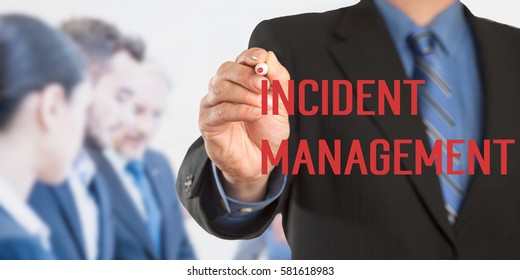 Incident Management, Male Hand In Business Wear Holding A Thick Pen Writing, With Office Team Blurred In Background, Digital Composing.