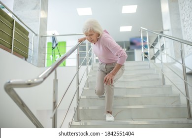 Incident. Senior Woman In Pink Shirt Falling Down On The Stairs