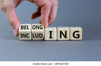 Including or belonging symbol. Businessman hand turns cubes and changes the word 'including' to 'belonging'. Beautiful grey background. Business and Including or belonging concept. Copy space.