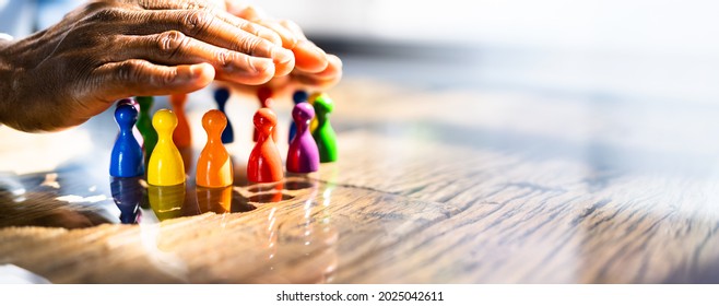 Inclusion, Diversity And Equality. African Hands Safeguard Wooden pawns - Shutterstock ID 2025042611